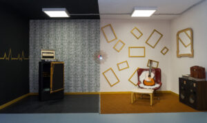 decorados. primer decorado tiene una pared de billetes y presetna una caja fuerte. El segundo decorado es una pared blanca con marcos dorados y hay una butaca roja. El estilo es vintage.